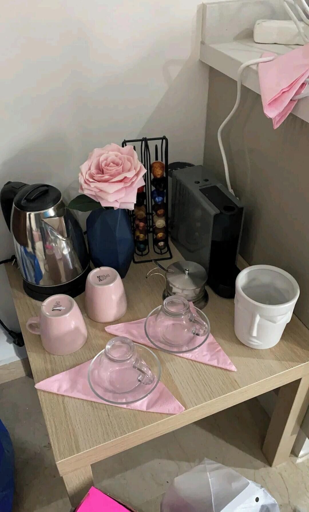Ein kleiner Tisch mit Wasserkocher, Blumenvase, Kaffeemaschine sowie verschiedenen Tassen und Gläsern.