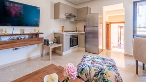 Eine moderne Küche mit großem Fernseher, Kühlschrank und Essbereich mit blumigem Sofa.