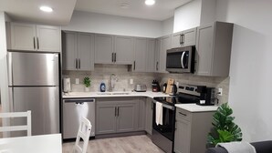 Una cocina moderna con armarios grises, electrodomésticos de acero inoxidable, lavavajillas y cafetera.