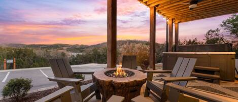 An outdoor seating area with a fire pit, wooden chairs, and a view of the landscape.