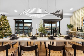 Un comedor moderno con una mesa larga dispuesta para varias personas, ventanas amplias y vistas al exterior.