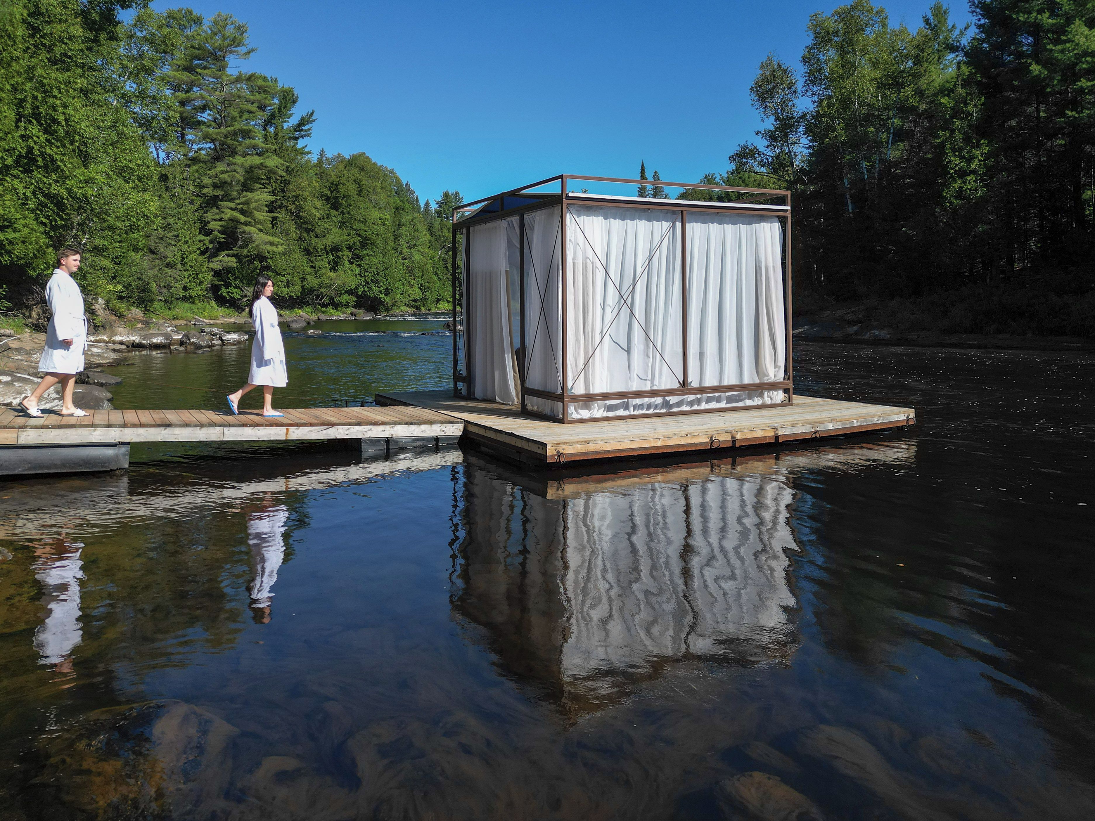 Un muelle de madera se adentra en una masa de agua con una pequeña construcción en él.