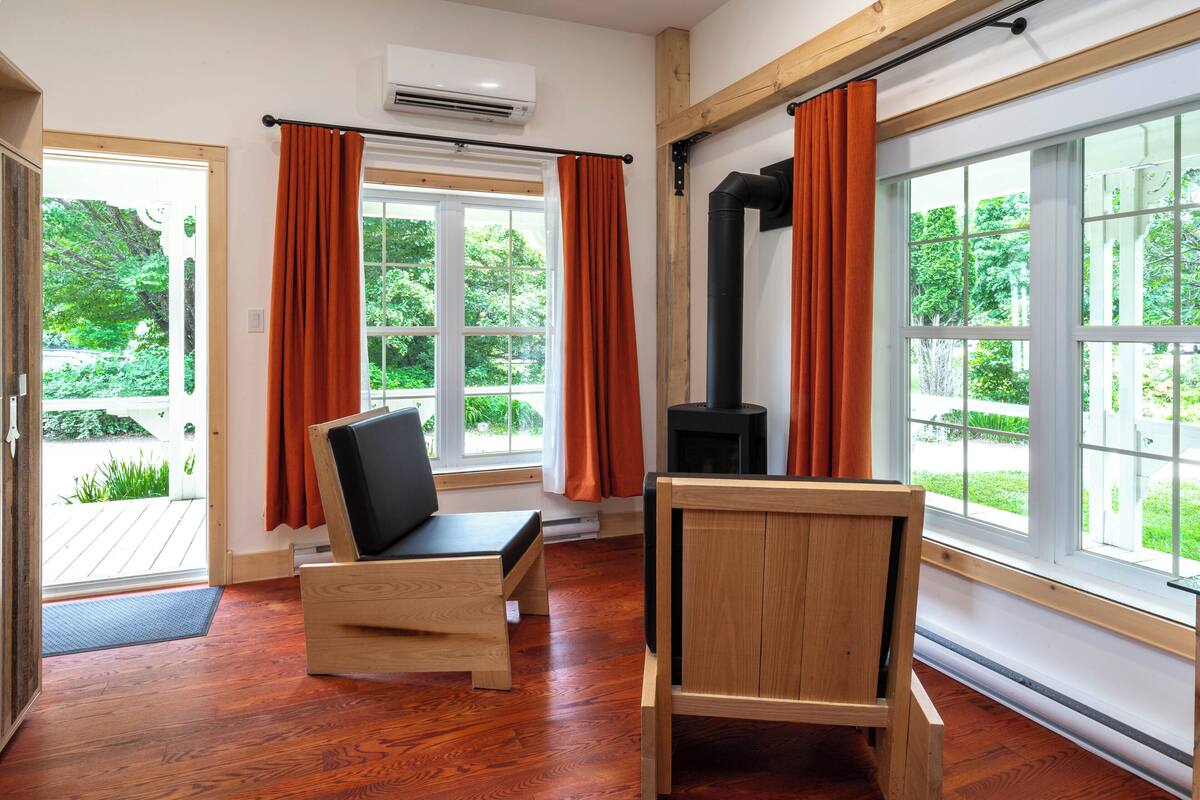 A room with wooden flooring, a black chair, a wooden table, and a fireplace.