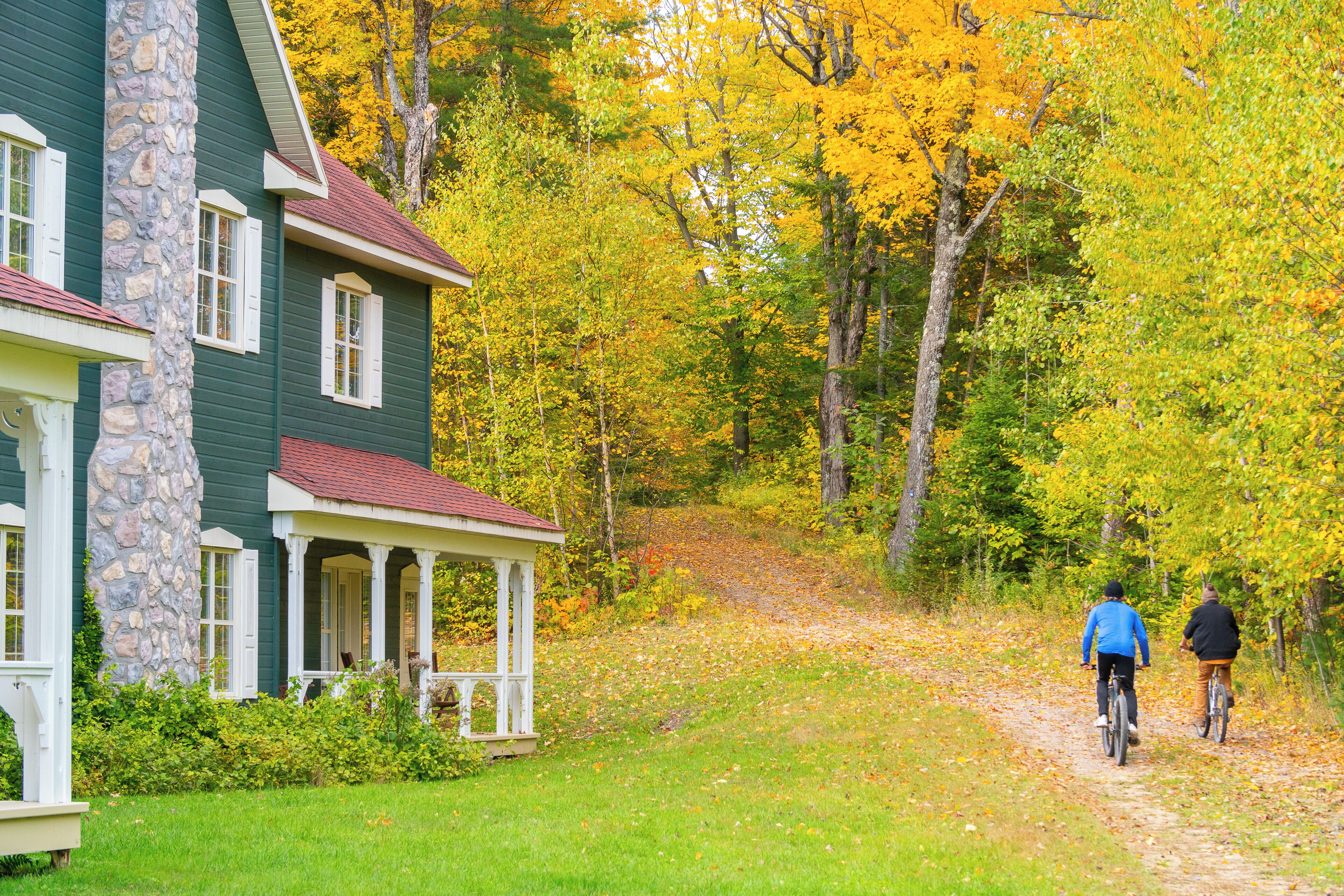 A house with a porch and stone pillar, surrounded by autumn foliage.