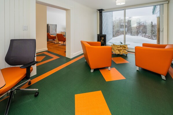 A modern interior with a green and orange carpet, orange chairs, and a large window with a view of a snowy landscape.