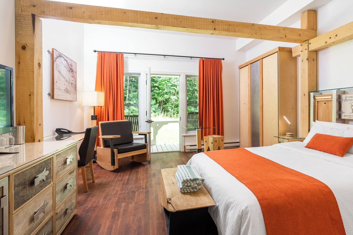 A hotel room with a bed, a desk, a chair, and a window with curtains.