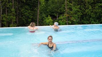 An outdoor swimming pool surrounded by dense green trees.