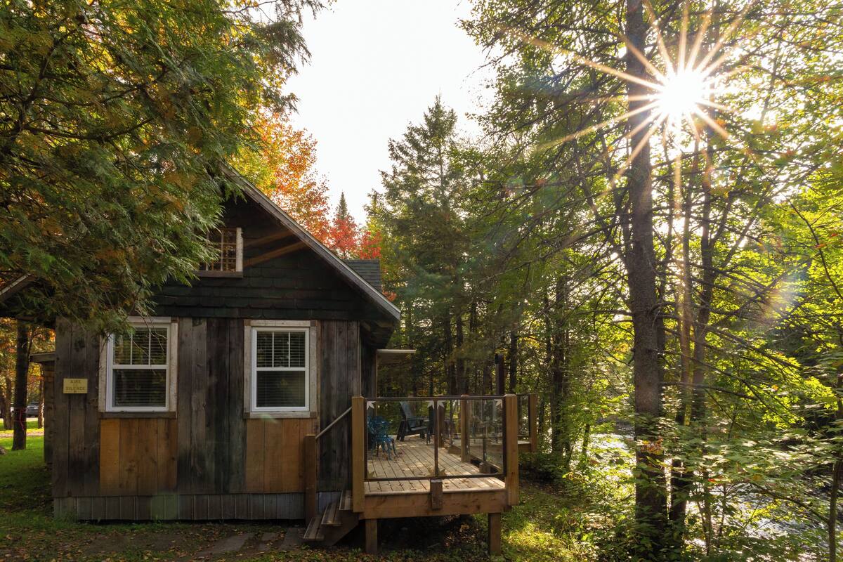 A cabin with a deck, surrounded by trees.