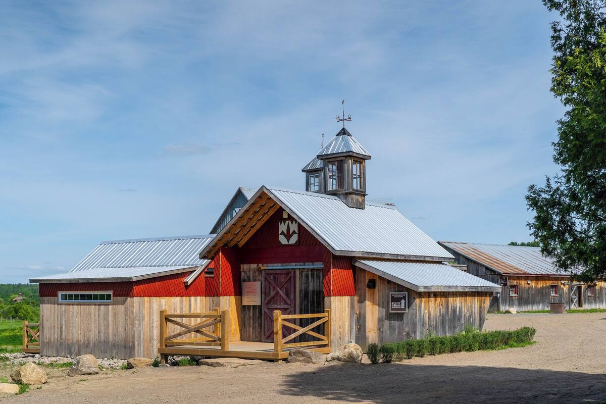 A rustic barn with a red facade, a wooden door, and a metal roof.