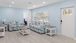Una habitación con pared azul claro, muebles blancos y una puerta con ventanal.
