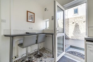 Et køkken med en bar, et vindue og udsigt til en stenvæg.