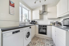 Een moderne keuken met een inbouw wasmachine, oven en een raam voor natuurlijk licht.