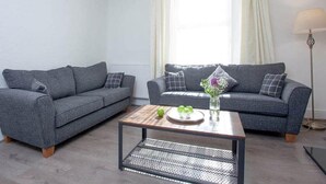 A living room with two grey sofas, a coffee table, and a floor lamp.