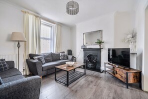A living room with a sofa, a coffee table, a fireplace, and a television.