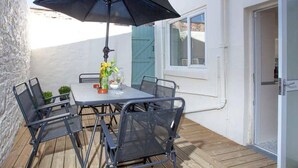 A patio with a table, chairs, and an umbrella.