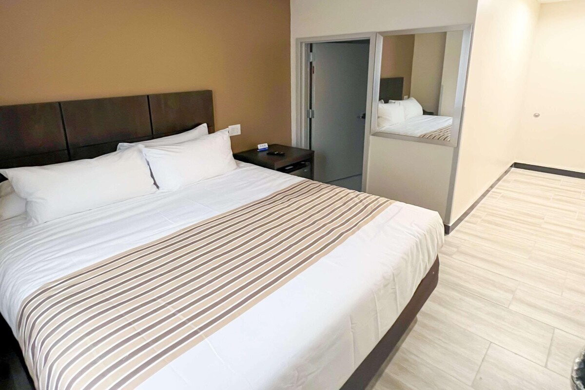 A hotel room with a large bed, a nightstand, a mirror, and a door leading to a closet.