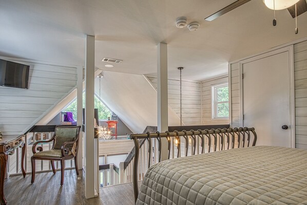 Un dormitorio con cama, una silla, una escalera y vistas al exterior.