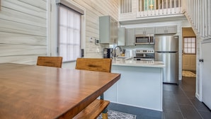 A modern kitchen with a central island, stainless steel appliances, and a dining area with wooden chairs.