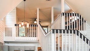 A multi-level interior with a staircase, a ceiling fan, and a kitchen area with cabinets and appliances.