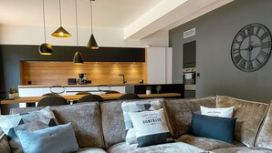 A modern living room with a sofa, coffee table, and a kitchen in the background.