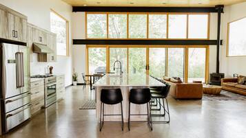 Una cocina amplia con isla central, electrodomésticos de acero inoxidable y ventanas grandes que ofrecen vistas al exterior.