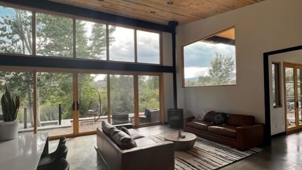 A spacious living area with a high ceiling, large windows, and a modern design.