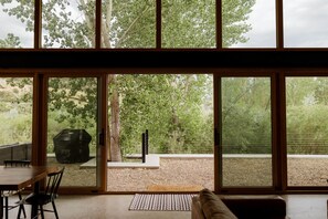 Un intérieur moderne avec de grandes fenêtres donnant sur un espace boisé.