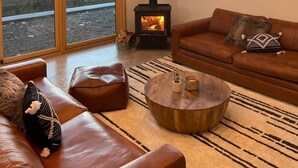 A spacious living room with a large fireplace, leather sofas, and a view of a mountainous landscape.