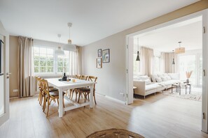 A spacious living area with a dining table, chairs, a sofa, and a coffee table.