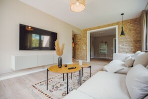 A modern living room with a flat-screen TV, a sofa, a coffee table, and a patterned rug.