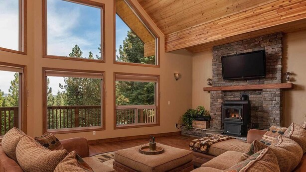 A spacious living room with large windows, a stone fireplace, and a cozy seating area.