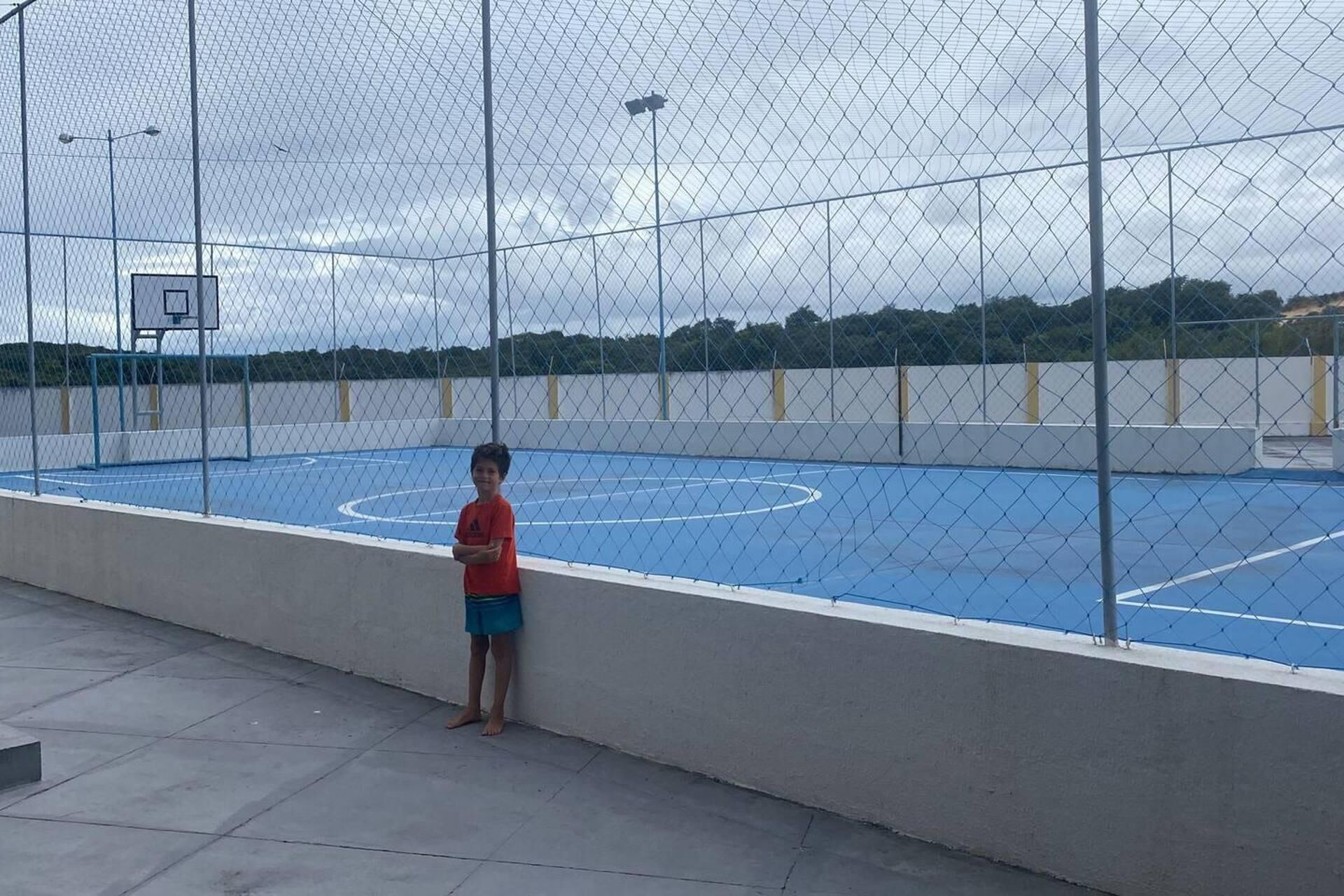 An outdoor basketball court enclosed by a chain-link fence.