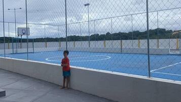 An outdoor basketball court enclosed by a chain-link fence.