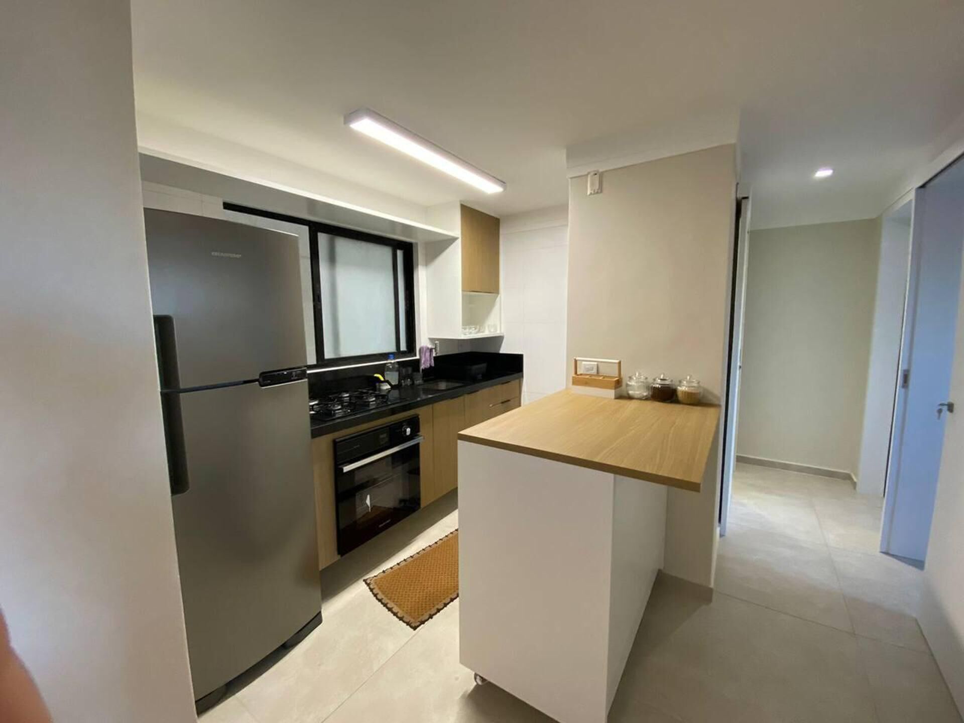 A modern kitchen with a refrigerator, stove, oven, and wooden countertop.