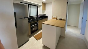 Uma cozinha moderna com geladeira, fogão, forno e bancada de madeira.