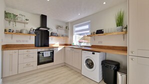 A modern kitchen with wooden countertops, built-in appliances, and decorative shelves.