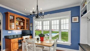 A kitchen with a dining area, wooden cabinets, a chandelier, and a view of a swimming pool. - Waterfront Home with Pool, Hot Tub, Dock & Sunset Views – Near St. Michaels (Tilghman Island)