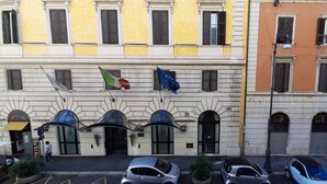 A building with multiple windows and a flag. There are parked cars in front.