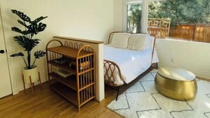 A bedroom with a bed, a wooden side table, a potted plant, and a view of the outdoors. - Luxe modern Lagunitas studio at Samuel P Taylor (Lagunitas-Forest Knolls)