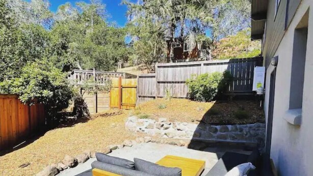 A backyard with a wooden bench and a stone wall. - Luxe modern Lagunitas studio at Samuel P Taylor (Lagunitas-Forest Knolls)