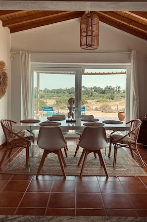 A dining area with a glass table, wicker chairs, and a view of a rural landscape.
