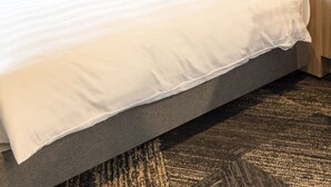 A neatly made bed with a grey headboard and white bedding in a hotel room. - Comfort Hotel Yokkaichi (Yokkaichi)