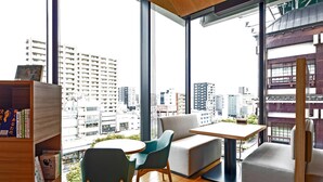 A modern room with a large window, a wooden bookshelf, a round table, and two chairs. - Comfort Hotel Yokkaichi (Yokkaichi)