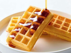 Dois waffles com xarope sendo derramado.