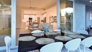 A modern dining area with a black table, white chairs, and decorative plants. - Pool/Spa-Location-Basketball-GameRoom-Specials ask (Bermuda Dunes)