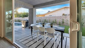 Moderni patio, jossa on pöytä ja tuolit, grilli ja uima-allas.