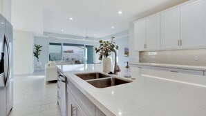 A modern kitchen with a large island, stainless steel appliances, and white cabinetry. - Pool/Spa-Location-Basketball-GameRoom-Specials ask (Bermuda Dunes)