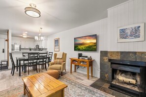 A modern living room with a fireplace, dining area, and kitchen in the background. - Hot Tub|True Ski-In/Ski-Out|Forest View Patio|Managed by Park City Lodging (Park City)