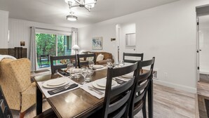 Ein Esszimmer mit einem Holztisch, gedeckt für vier Personen, umgeben von dunklen Holzstühlen.