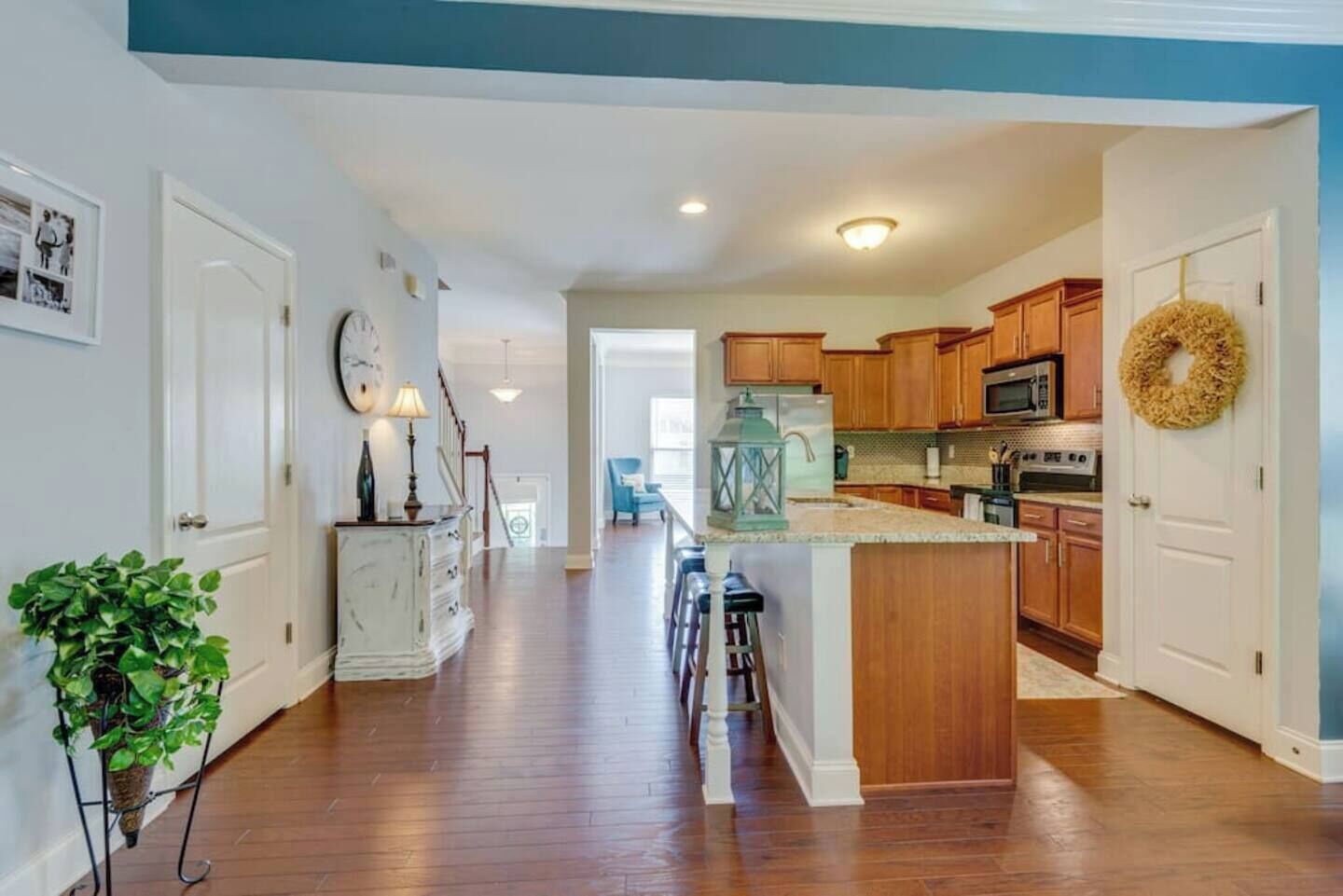 A modern kitchen with wooden cabinets, a central island, and a dining area with bar stools.